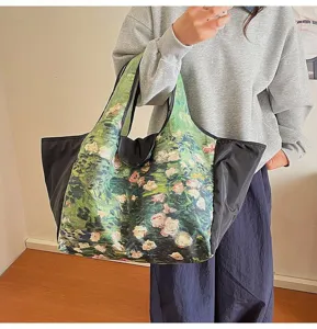 A model carries a large green floral tote with black side panels and twin handles indoors