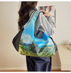 Rear view of a person carrying a large shoulder tote with a vivid blue and green landscape print