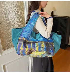 Woman carrying a large teal tote bag with vivid blue and yellow oil-painting artwork