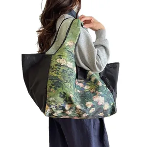 Large tote shopping bag with black panels and green floral oil-paint print, carried over the shoulder