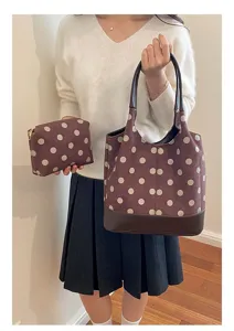 Een vrouw toont een mauve tas met stippen en bijpassend etui, dubbele hengsels en donkerbruine bodem