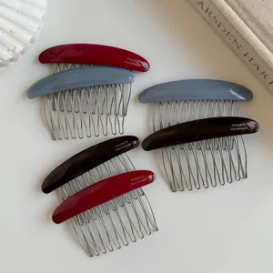 Six curved hair combs with red, gray and black resin-look backs and metal teeth arranged on a white surface