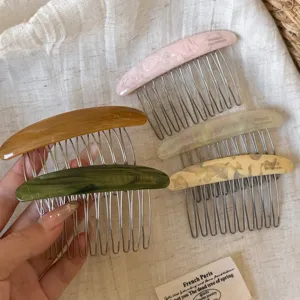 Five resin hair combs with metal teeth in assorted tortoiseshell colors, displayed on linen fabric