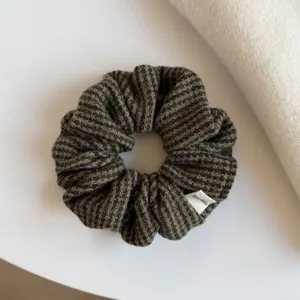 Gros plan sur un chouchou froncé en tissu à carreaux, aux tons vert foncé, brun et beige