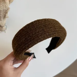Close-up van een bruine, pluizige haarband met breistructuur en zwarte stoffen voering