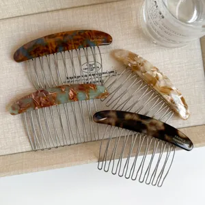 Four resin hair combs with metal teeth in tortoiseshell, green marble, ivory and brown patterns