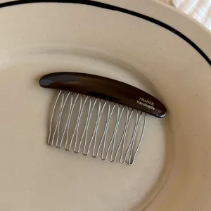 Close-up of a dark brown resin comb with silver metal teeth and "FRANCE Handmade" lettering