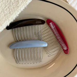 Overhead view of three resin hair combs in brown, blue-gray, and red with fine metal teeth
