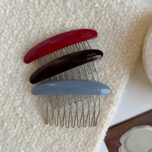 Three resin combs in burgundy, dark brown and blue-gray, with fine metal teeth, laid flat