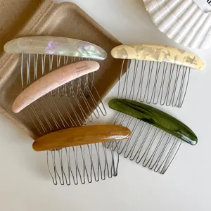 Five colorful resin combs with metal teeth, arranged on brown card against a white background