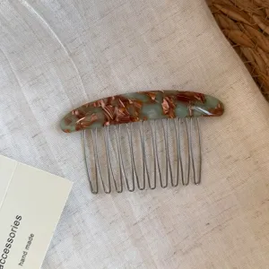 Flat lay of a brown-green marbled acetate hair comb with slender metal teeth on linen fabric