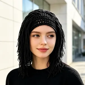 Model wearing a black open-knit cap with long braided fringe, photographed outdoors in soft light