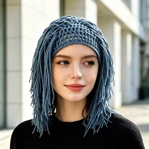 Portrait of a woman wearing a grey-blue open-knit cap with long yarn fringe framing her face