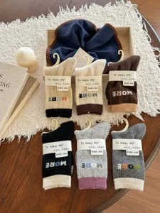 Overhead view of assorted wool-blend crew socks with contrasting cuffs, arranged on a wooden table