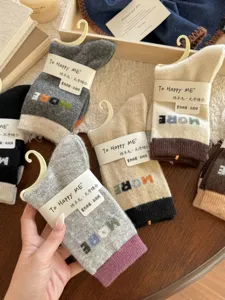 Assorted wool-blend socks with contrast cuffs and colorful lettering, arranged on a wooden table