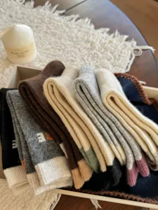 Close-up of folded multicolored knit socks arranged in a wooden box on a soft winter textile