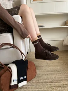 Lifestyle view of brown knit socks with beige cuffs and MORE lettering, worn with suede shoes