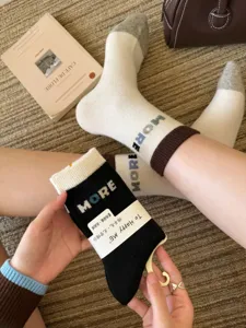 Close-up of knit mid-calf socks with contrast cuffs and heels, plus visible MORE lettering