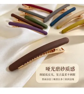 Gros plan sur une barrette brune mate à fermoir doré, parmi des barrettes colorées sur la soie