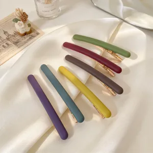 Lot de six barrettes mates de couleurs variées, avec pinces métalliques dorées, disposées sur du satin