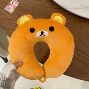 Close-up of an orange plush bear face, yellow-lined ears, embroidered features and clasp