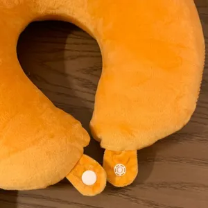 Close-up of orange plush U-shaped travel neck pillow with soft pile fabric and snap fasteners