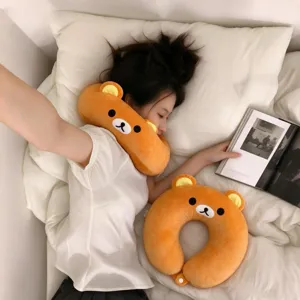 Overhead view of a person resting with an orange bear plush neck pillow and matching U-shaped pillow