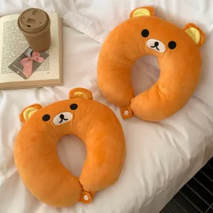 Two orange plush bear-shaped neck pillows with embroidered faces and round button closures