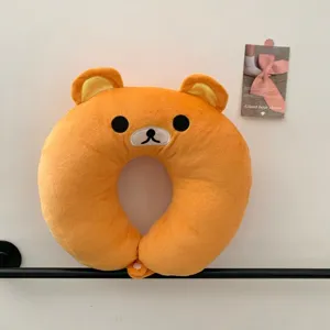 Front view of an orange plush bear face with embroidered features and a snap closure at the base