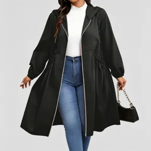 Full-length view of a model in a black hooded coat, cinched waist, zip front, and blue jeans