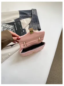 Dettaglio di una piccola borsa rosa aperta, con fodera scura, chiusura dorata e finiture metalliche