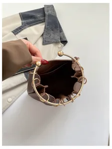 Vista dall’alto di una borsa marrone aperta, con manico circolare dorato e dettagli metallici
