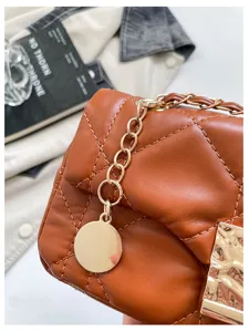 Primo piano di una borsa marrone trapuntata a rombi, con catena dorata e ciondolo tondo