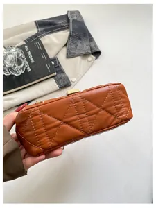 Primo piano della similpelle marrone, trapuntatura a rombi e cuciture sul fondo della borsa