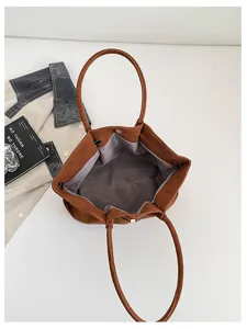 Overhead view of an open brown faux suede tote, showing its gray fabric lining and gold snap closure