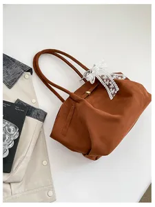 Overhead view of a soft brown bag with matching handles, lace ribbon trim and small metal accents