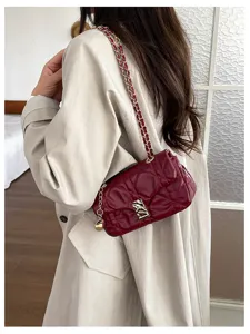 Borsa a tracolla bordeaux trapuntata indossata, con catena dorata e chiusura in metallo