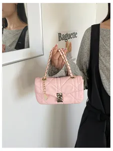 Borsa rosa trapuntata con manici a catena dorati e chiusura, mostrata tenuta accanto alla persona