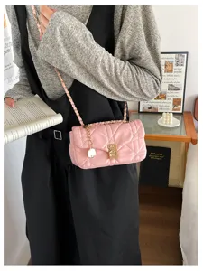 Borsa rosa trapuntata con catena e chiusura dorate, indossata sopra un abito nero al chiuso