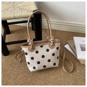 Borsa a pois con manici beige annodati e tracolla rimovibile, su un tappeto accanto ai libri