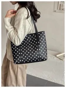 Vista laterale di una modella con una borsa nera a pois bianchi e lunghi manici da spalla