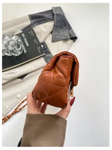 Primo piano del lato della borsa marrone trapuntata, dalla forma compatta e con catena dorata