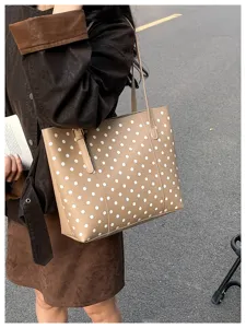 Vista urbana della borsa beige a pois bianchi portata a spalla durante una passeggiata in città