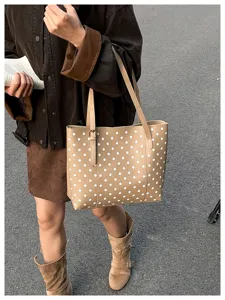 Scena di strada con una borsa color cammello a pois bianchi, portata accanto a un libro