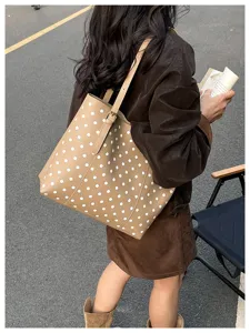 Scena d’uso: borsa tote in similpelle color cammello a pois bianchi portata a spalla all’aperto