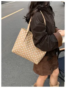 Scatto street style di una borsa color cammello a pois bianchi portata a spalla dalla modella