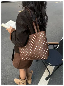 Scena urbana: una donna porta a spalla una borsa marrone con pois bianchi, vista da dietro