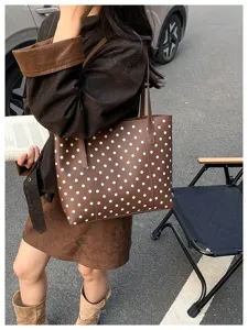 Scena di strada con una modella che porta a spalla una borsa marrone a pois bianchi
