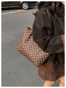 Scena di strada con borsa marrone a pois bianchi e chiusura metallica, portata a spalla