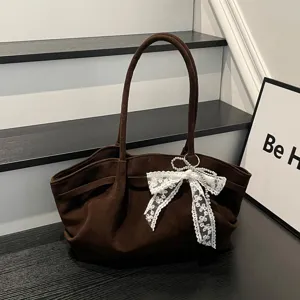 Brown soft-textured bag with gathered fabric, long handles, lace bow and pearl accents on display